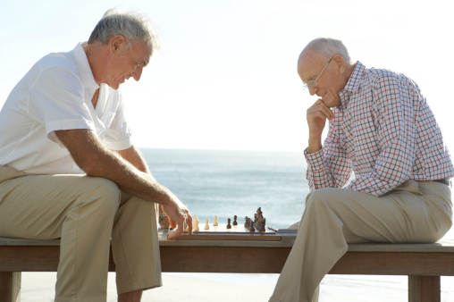 Two Senior Men Playing Chess, with the Sea in the Background